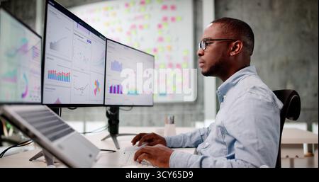 Focused African American Man Analyzing Financial Data On Laptop Screen. Stock Photo
