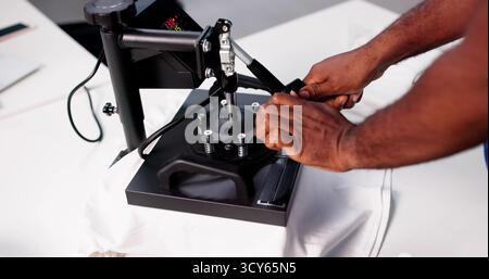 The Expert T-Shirt Printer In His Shop Creating Custom Designs Stock Photo