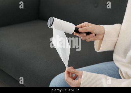 Woman removing sticky tape from lint roller at home. Space for text Stock Photo