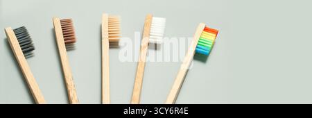 Bamboo toothbrushes with multicolored bristles on gray background for eco-friendly oral care. Stock Photo