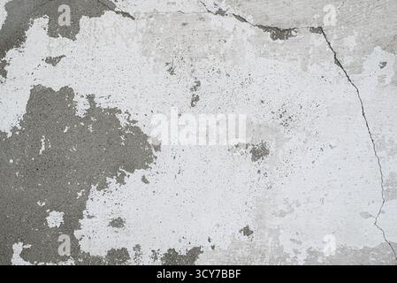 Old concrete or plastered wall with peeling paint. Abstract vintage grunge background with cracks, abrasions and unevenness. Stock Photo