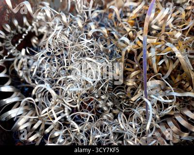 Metal shavings are piled together, showcasing the remnants of steel after the turning process in an industrial workshop. It highlights precision work. Stock Photo