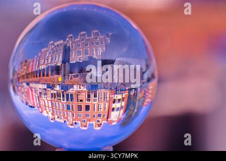Glass sphere on a rail showing an inverted row of canal houses with stepped gables and windows, shot with shallow depth of field and soft bokeh light. Stock Photo