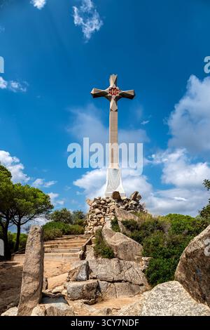 Pedestal in the form of a large stone cross, installed on the top of a mountain, against the backdrop of a blue sky. Stock Photo