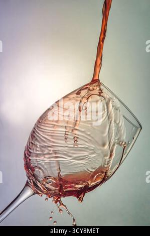 Close-up of red wine pouring into a tilted glass. Splashes and bubbles create a dynamic, vibrant scene with rich color and elegant motion. Stock Photo