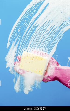 Man washes glass with sponge on blue background Stock Photo