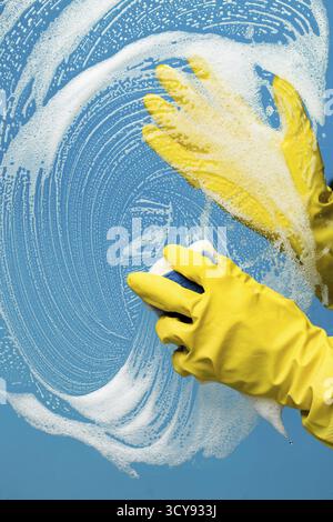 Man washes glass with foam on blue background Stock Photo