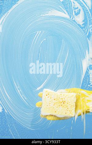 Man with sponge cleaning window on blue background Stock Photo