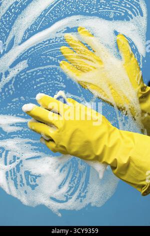 Person washes window with foam on blue background Stock Photo
