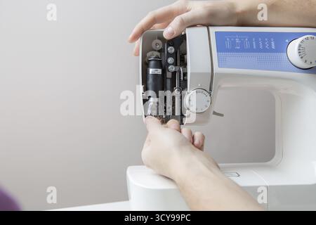Master repairing white sewing machine standing on blank gray background Stock Photo