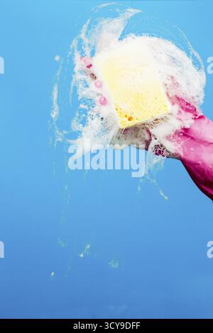 Man with foam sponge washes window on blue background Stock Photo