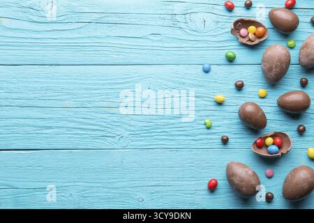 Halves of chocolate eggs, sweets on blue wooden table Stock Photo