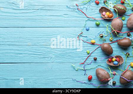 Chocolate eggs, multi colored sweets on wooden blue table, place for text Stock Photo