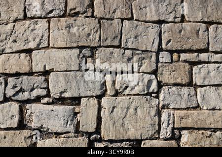 background, wall, rectangular-shaped stones stacked to form a sturdy structure. non-uniform concept image with light-colored stones of varying sizes Stock Photo