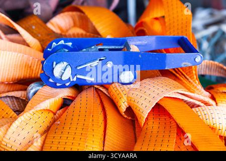 The ratchet lock lies on a pile of cargo straps, close-up Stock Photo