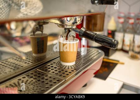 Coffee machine pouring coffee into a paper cup, close up Stock Photo