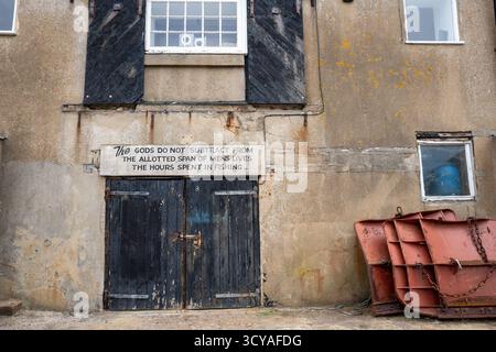 Old fishing building with black painted window shutters and double doors along the Cobb Harbour in the coastal town of Lyme Regis on the Dorset coast. Stock Photo