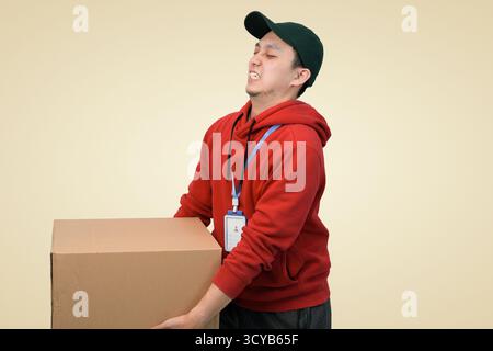 young man package delivery heavily lifted in studio background Stock Photo