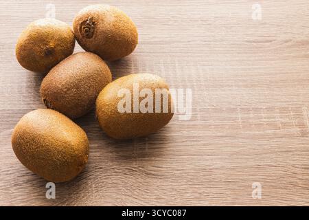 Bunch of kiwi fruit on a wooden table. There are five kiwi fruits in the bunch Stock Photo