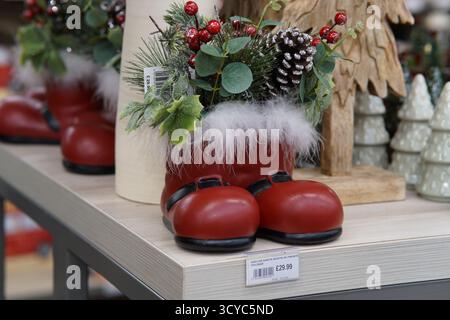 Red Santa boot decoration filled with pine cones, berries and greenery on festive display at Haskins Garden Centre. Haskins Garden Centre, Snowhill Stock Photo