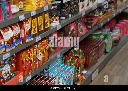 Assorted Christmas chocolates and festive gift boxes neatly arranged on retail shelves at Haskins Garden Centre during the holiday season. Stock Photo
