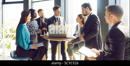 Multiethnic workers, business people with laptop meeting in modern office hall, talking, discussion Stock Photo