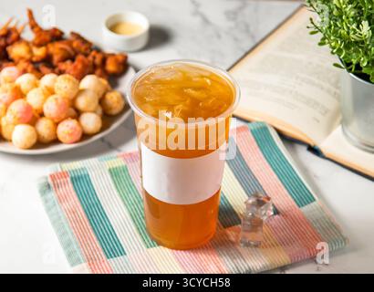 Iced green tea with ice cube served in plastic glass with ice cube isolated on napkin side view of taiwan cold drink Stock Photo