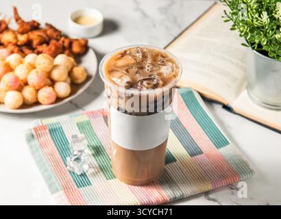 Iced cream milk tea with boba and ice cube served in plastic glass with ice cube isolated on napkin side view of taiwan cold drink Stock Photo