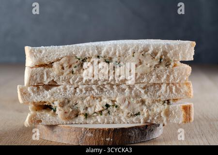 Close-up of a generously filled chicken and stuffing sandwich stack, cut in half, resting on a rustic wooden coaster, ready for a delicious lunch Stock Photo