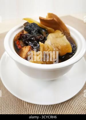 Agaricus Blazei, Fish Maw, Conch Head and Bamboo Chicken Soup served in broth isolated on background closeup top view of Hong Kong food Stock Photo