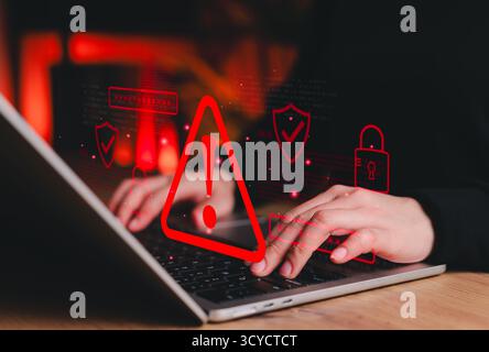 Cybersecurity alert concept. Person using laptop showing red warning symbol representing data breach, system hacking notification, cyber risk Stock Photo