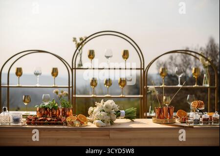 Elegant outdoor bar setup with gold accents and floral wedding bouquet. Stock Photo