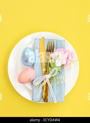 Happy Easter. Easter celebration concept. Top view vertical Napkin empty white and yellow plate, Easter eggs, on isolated yellow background. Copy spac Stock Photo