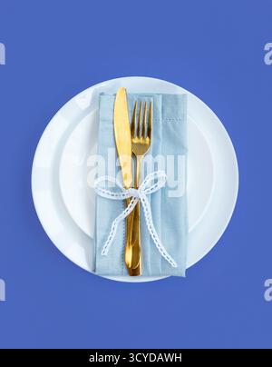 Happy Easter. Easter celebration concept. Top view vertical Napkin empty white and yellow plate, Easter eggs, on isolated blue background. Copy space, Stock Photo