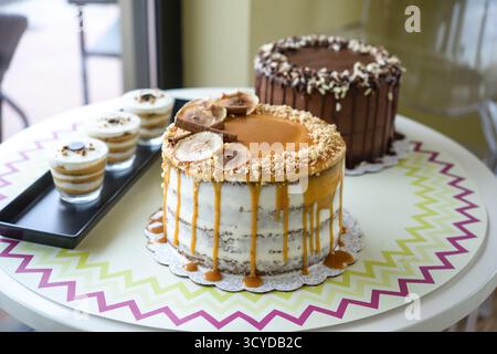 Assorted Cakes and Desserts on Display include caramel cake with fig slices, a chocolate cake with sprinkles, and layered dessert cups side view of sw Stock Photo