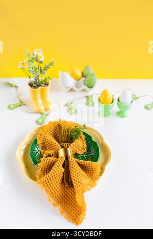 Happy Easter. Easter celebration concept. Top view vertical Napkin empty green and yellow plate, Easter eggs, on isolated white background. Copy space Stock Photo