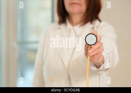 Close-up of experienced doctor in white uniform using stethoscope diaphragm. Focus on respiratory assessment, pneumonia, bronchitis, and patient care in clinical setting. Stock Photo
