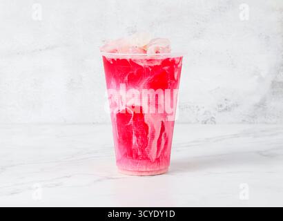 bandung drink or Ice Rose Milk Tea with ice cubes served in plastic cup isolated on marble background side view of Singapore beverage Stock Photo