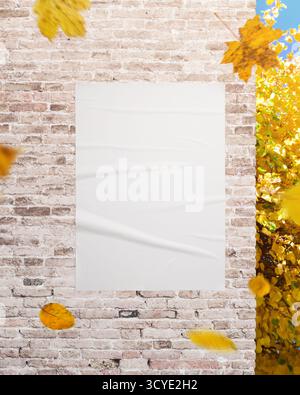 Vertical white poster on textured wall with yellow leaves, perfect for advertising, campaign visuals and design presentations Stock Photo