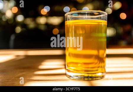 Vietnames tea in a clear glass sitting on a beige table with shadows from hard light. Stock Photo