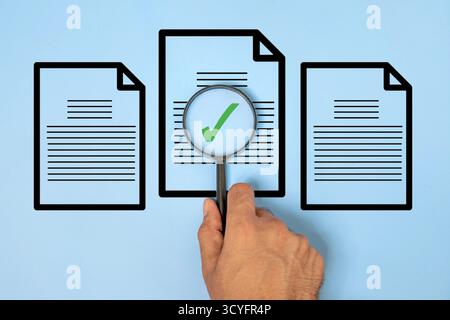 Hand holding a magnifying glass over a document with a green check mark. Document verification, quality control, audit, approval, compliance. Stock Photo