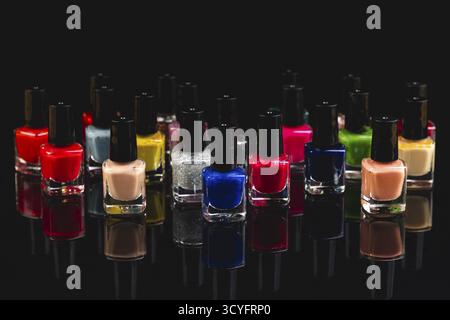 Different bottles of colored nail polishes with reflection on black background Stock Photo