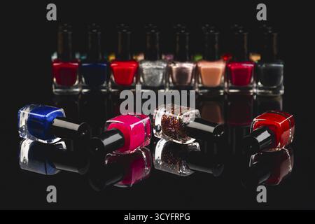 Different nail polish bottles in intense colors on a black surface with reflection Stock Photo