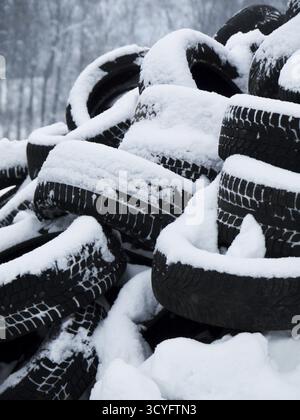 Pile of tires covered in snow. The tires are stacked on top of each other, creating a large mound. Concept of abandonment and neglect, as the tires ar Stock Photo