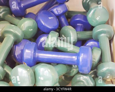 A pile of green and blue dumbbells with the numbers 1 and 2 on them. The dumbbells are stacked on top of each other Stock Photo