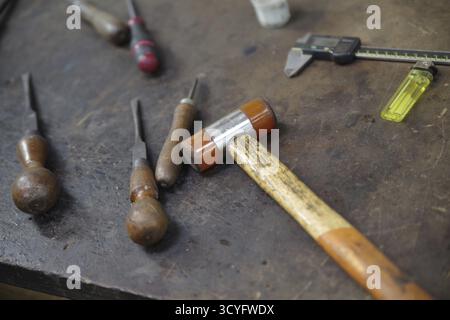 Table with a hammer and a few other tools on it. The hammer is the largest tool and is in the middle of the table Stock Photo
