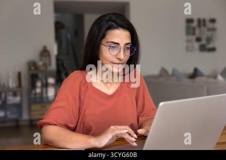 Busy Latin freelance professional woman in glasses working at home Stock Photo