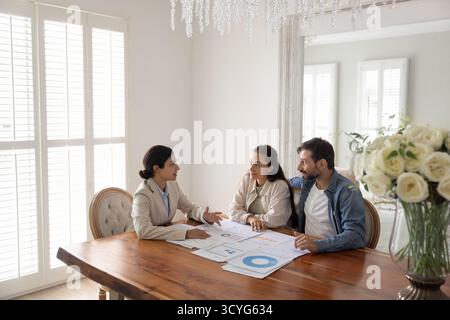 Focused husband wife talking with female financial advisor at table Stock Photo