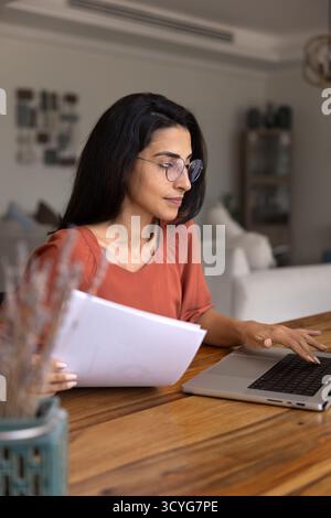 Busy young Hispanic business woman wearing glasses, working at home Stock Photo