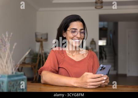 Happy Hispanic freelance business woman in glasses using online application Stock Photo